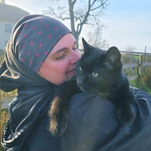 Schwarze Katze entspannt im Arm eines Menschen als Zeichen von Vertrauen und gewandelter Lebensqualität